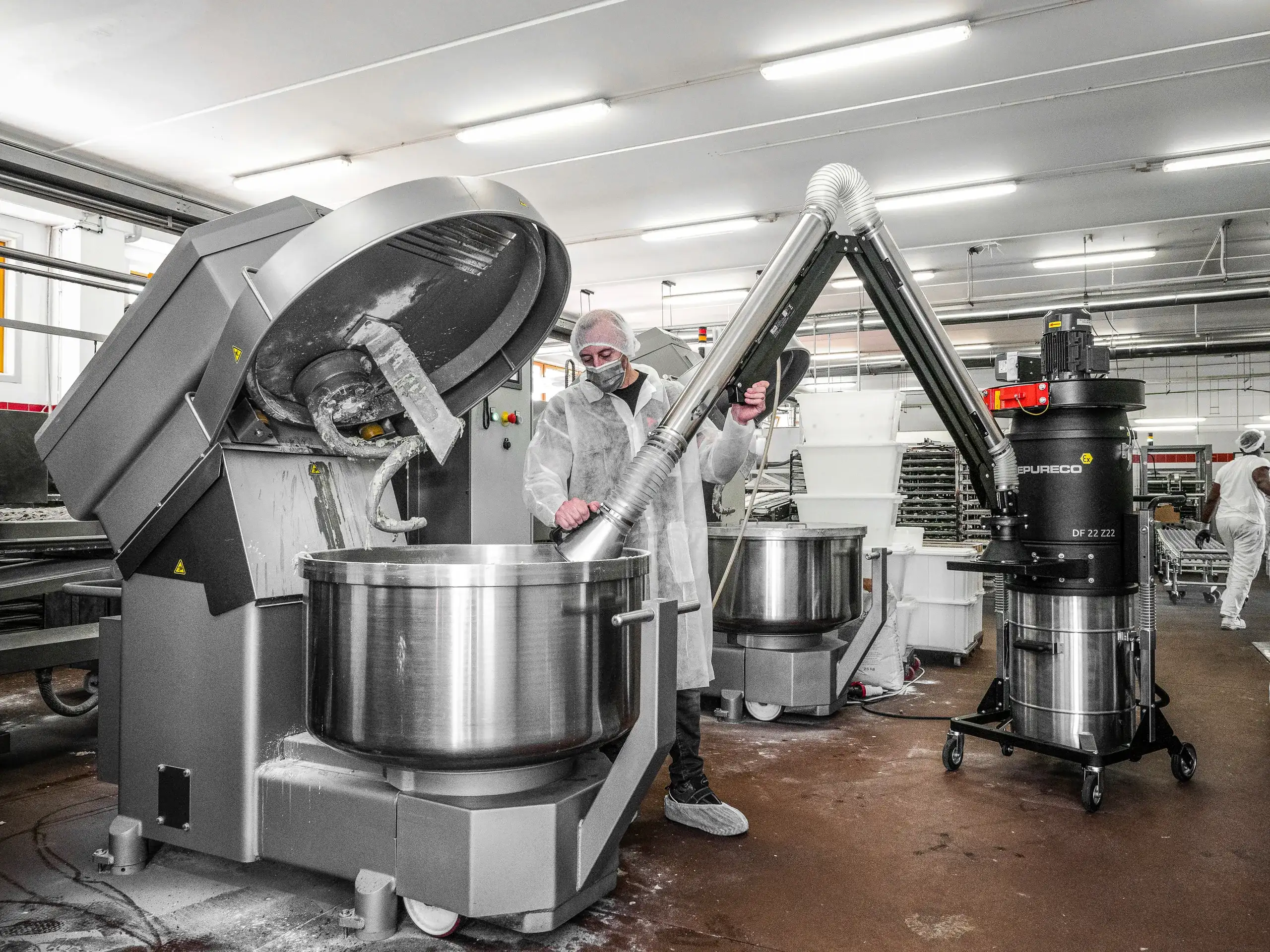 Stationary industrial vacuum recovering dry metal chips on a CNC machining line